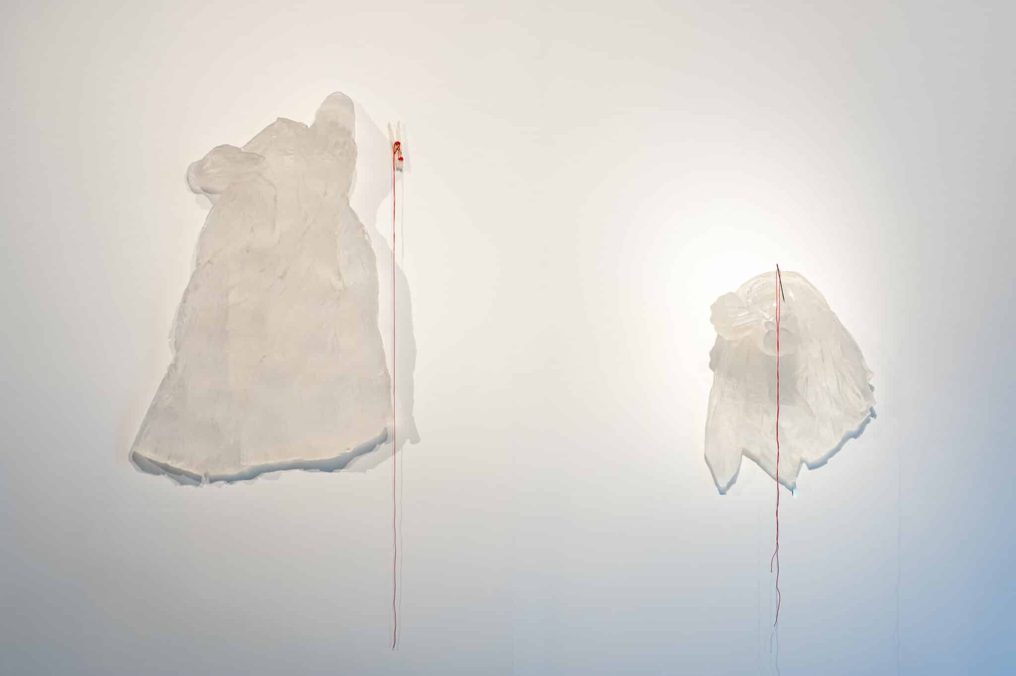 Image of artwork by Cassandra Straubing. "He built this house a century ago, only to find out it was torn down and erased by gentrification", 2018. Kilncast glass, blown glass, ring shanked nail, cotton thread. 30 x 13.75 x 5.875 inches